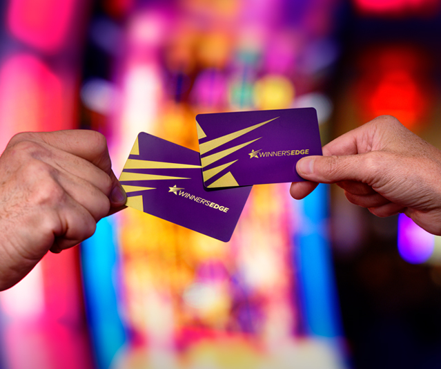 Two hands holding Winner’s Edge membership cards