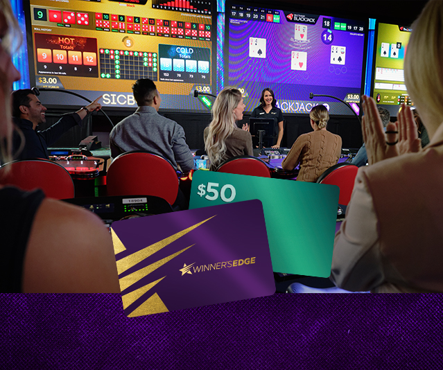 Players sitting in a casino facing large screens. 
